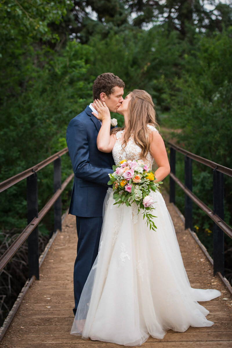 Elopement Photographer,  a bride and groom kiss on a foot bridge high in the forest