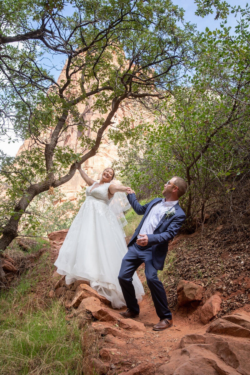 Bride and groom walk down a path in Zion National Park on their adventure elopement day.