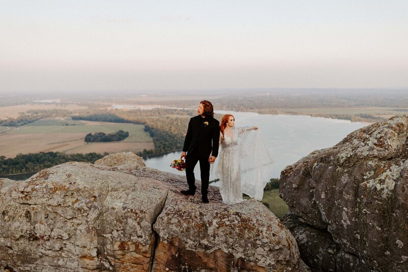An eloping couple stands on a large boulder atop Petit Jean Mountain in Arkansas.