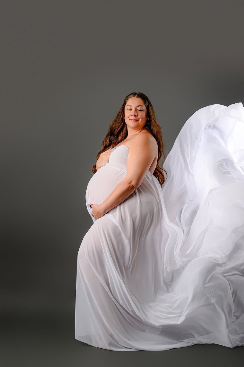 Charlotte expecting mom wrapped in a white chiffon wrap  flowing behind her