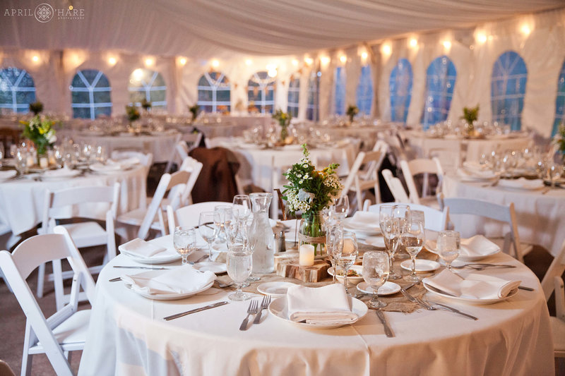 Round Tables set up for a wedding reception in the white tent with the sides closed at Boulder Creek by Wedgewood Weddings venue in Colorado
