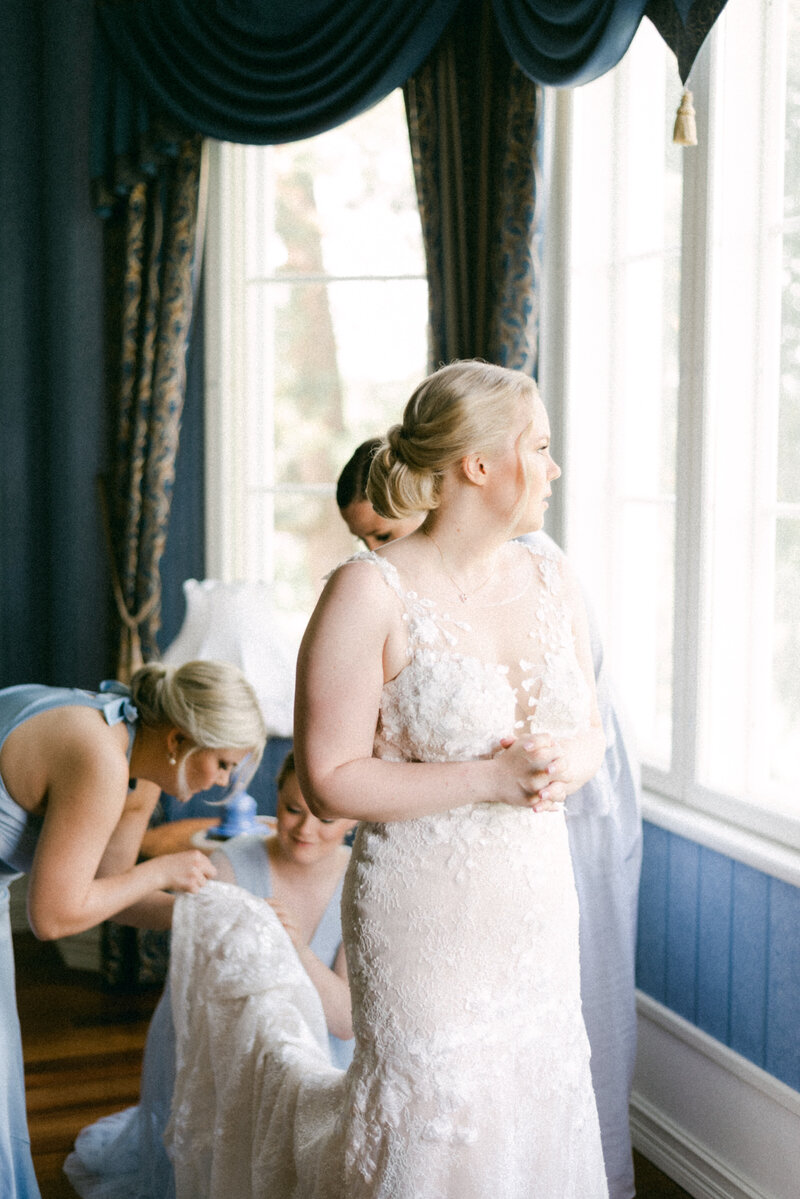 Bridesmaids are solving a problem with the wedding dress in an image photographed by wedding photographer Hannika Gabrielsson.