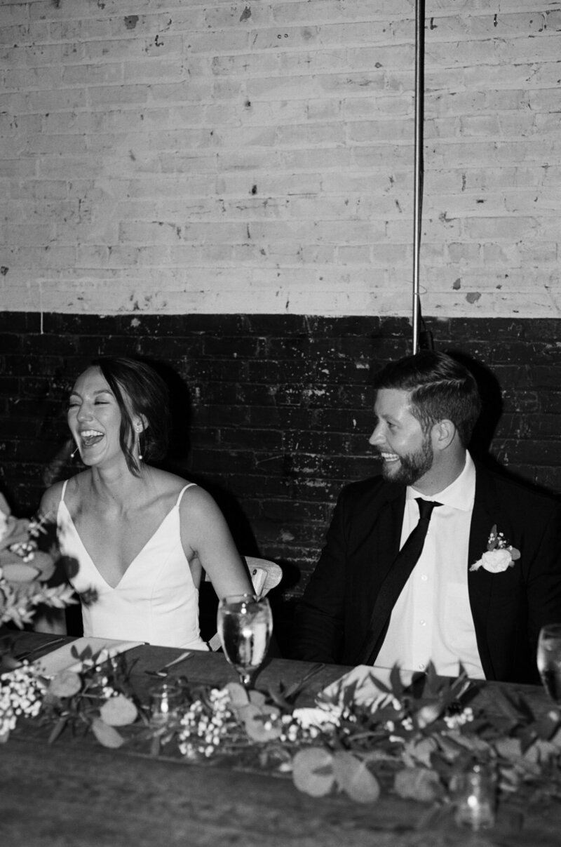 Black and white photo of happy couple smiling and walking down the aisle