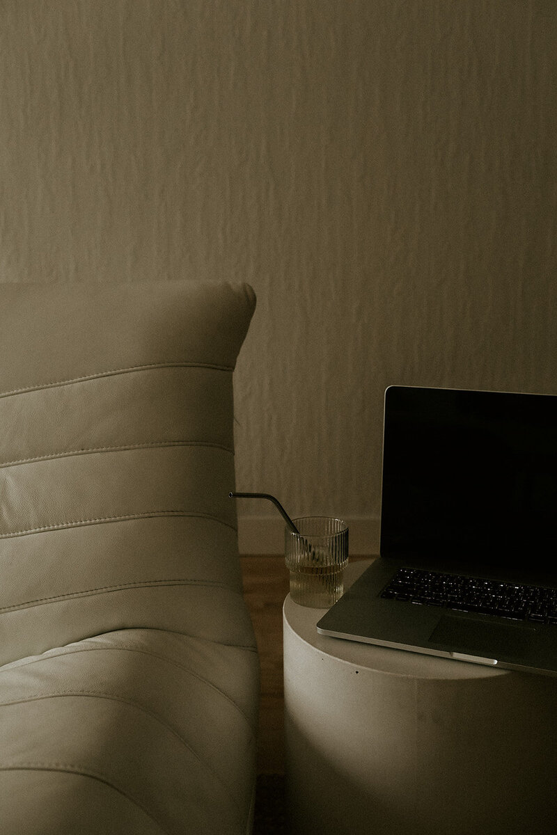 Laptop on a round side table next to a futon