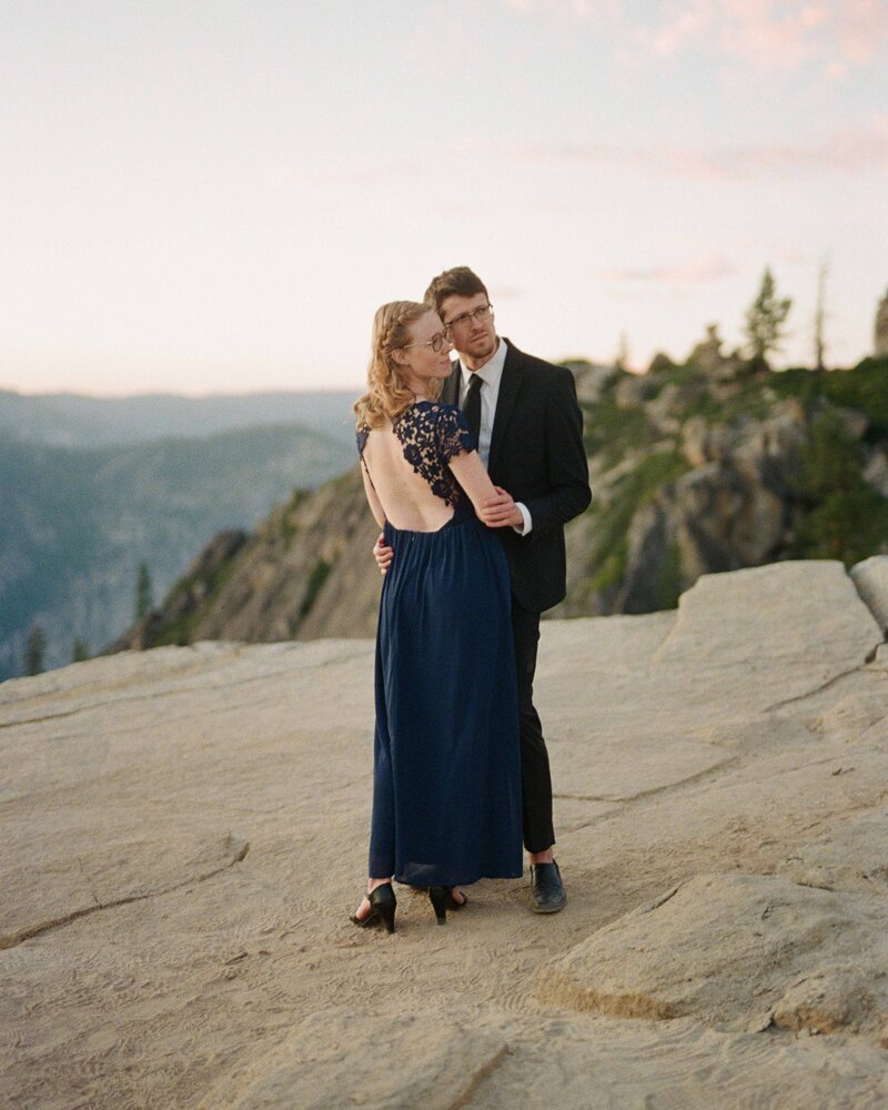 A loving couple embraces on the edge of Taft Point, Yosemite, with breathtaking cliffside views.