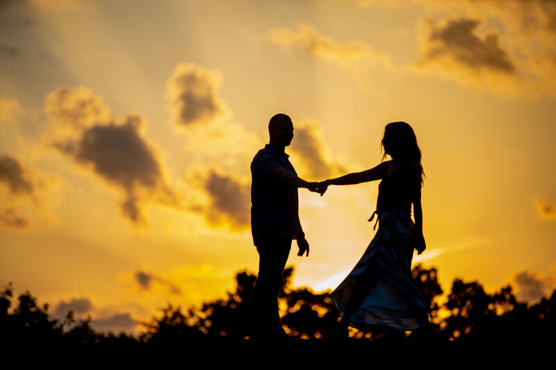 A silhouette wedding photo of a bride and groom dancing.