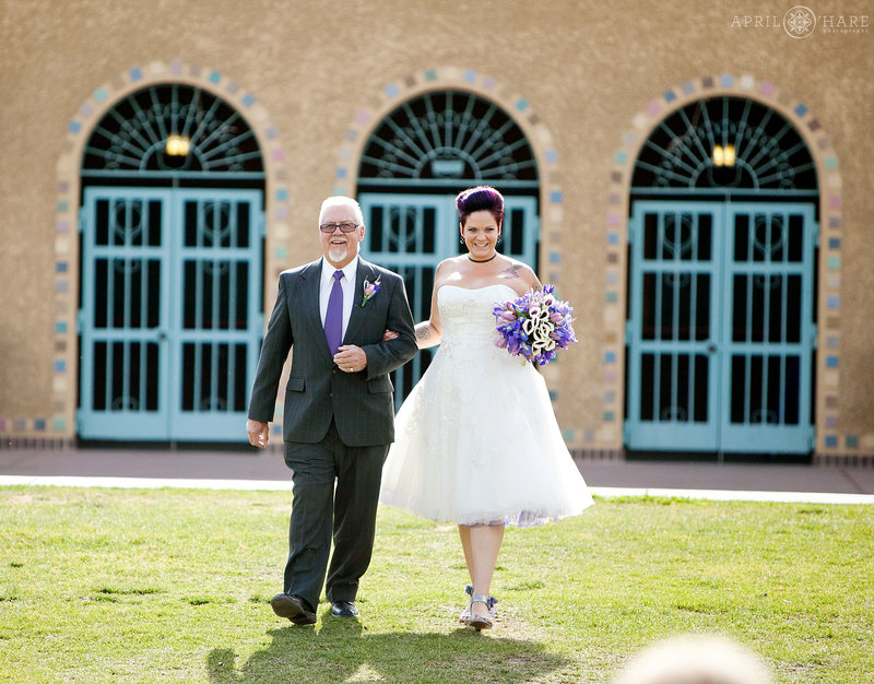 Bride walks with her dad to outdoor City Park Pavilion Wedding in Denver on a hot summer day