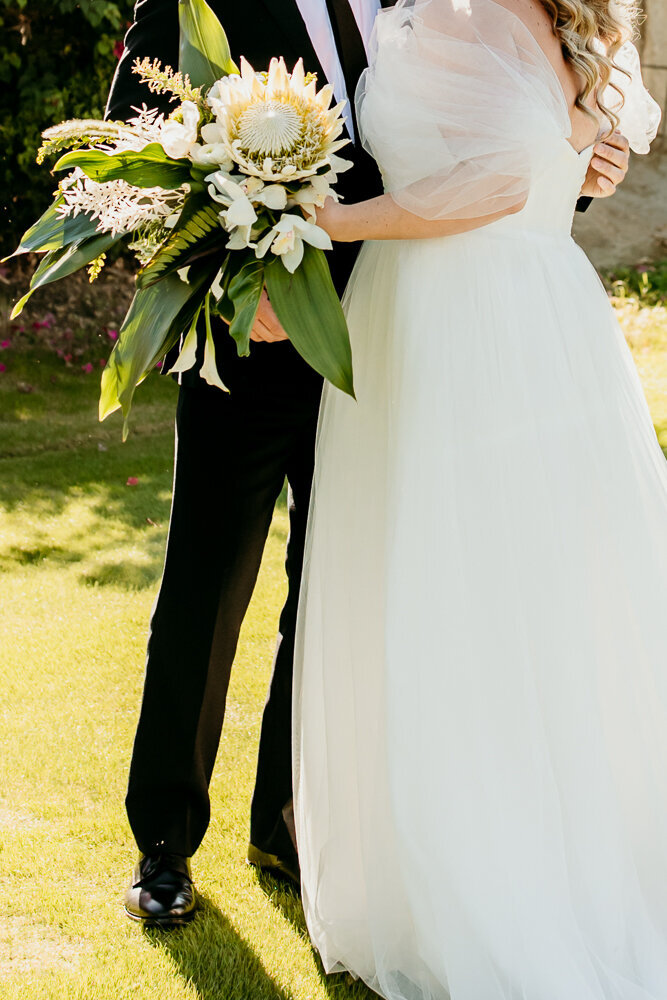 married couple hugging each other close and holding bouquet