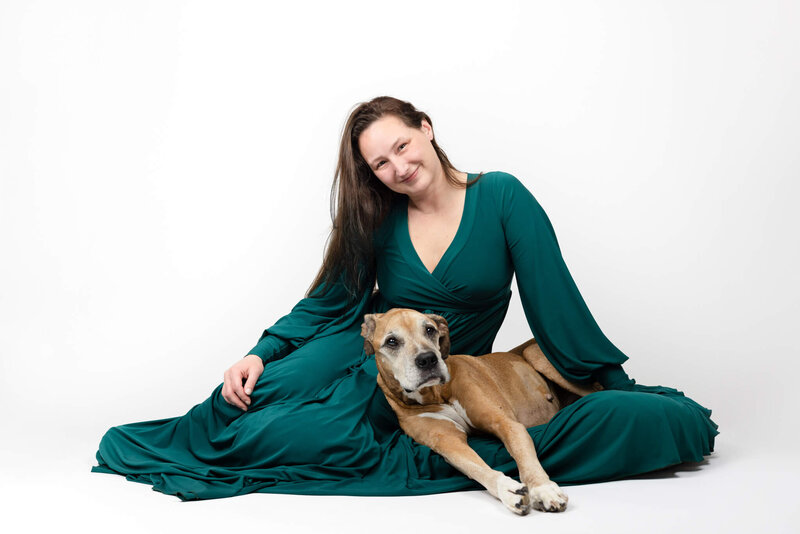 Boxborough Veteran and LGBT female photographer wearing a rgeen gown sitting with her elderly end of life Boxer/American Bulldog mix dog