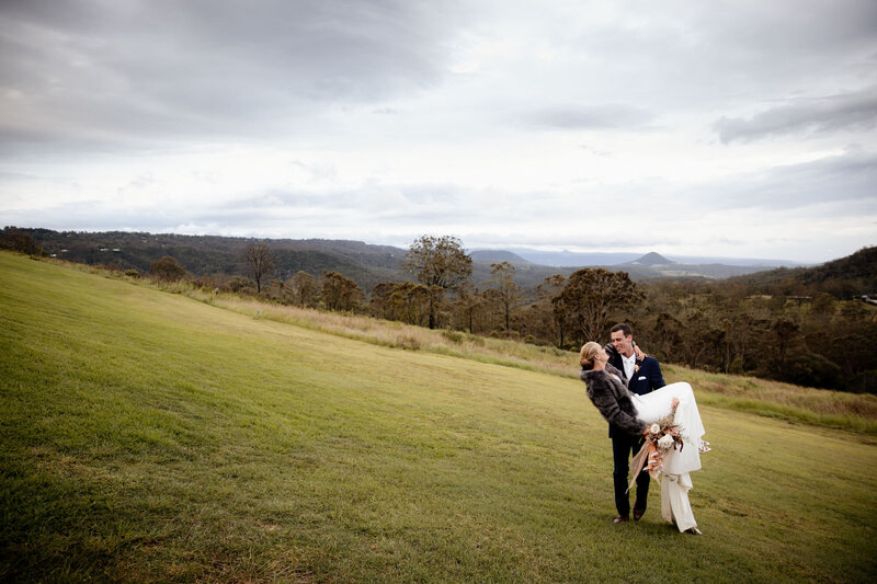 Groom lifts his bride in the green field