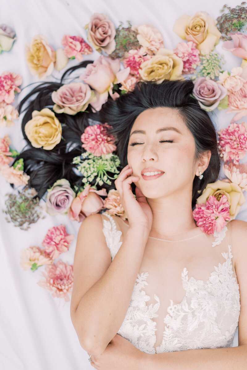 24-alisonbrynn-Radiant-LoveEvents-Maxwell-1-House-bride-laying-down-chest-up-black-hair-flowing-with-roses-flowers-drizzled-everywhere-on-hair-romantic-elegant-timeless