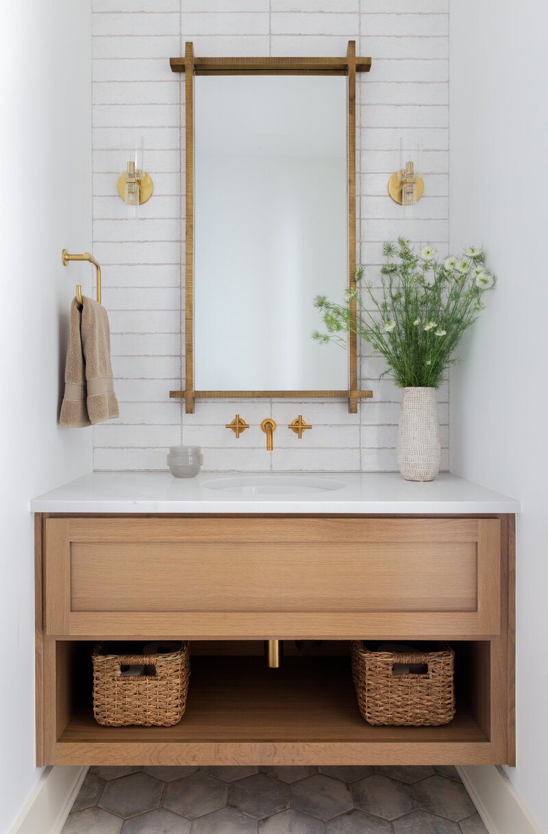 Clean and Bright bathroom with floating vanity, large subway tiles and geometric mirror. Modern brass sconce lighting with brass faucets and pea trap