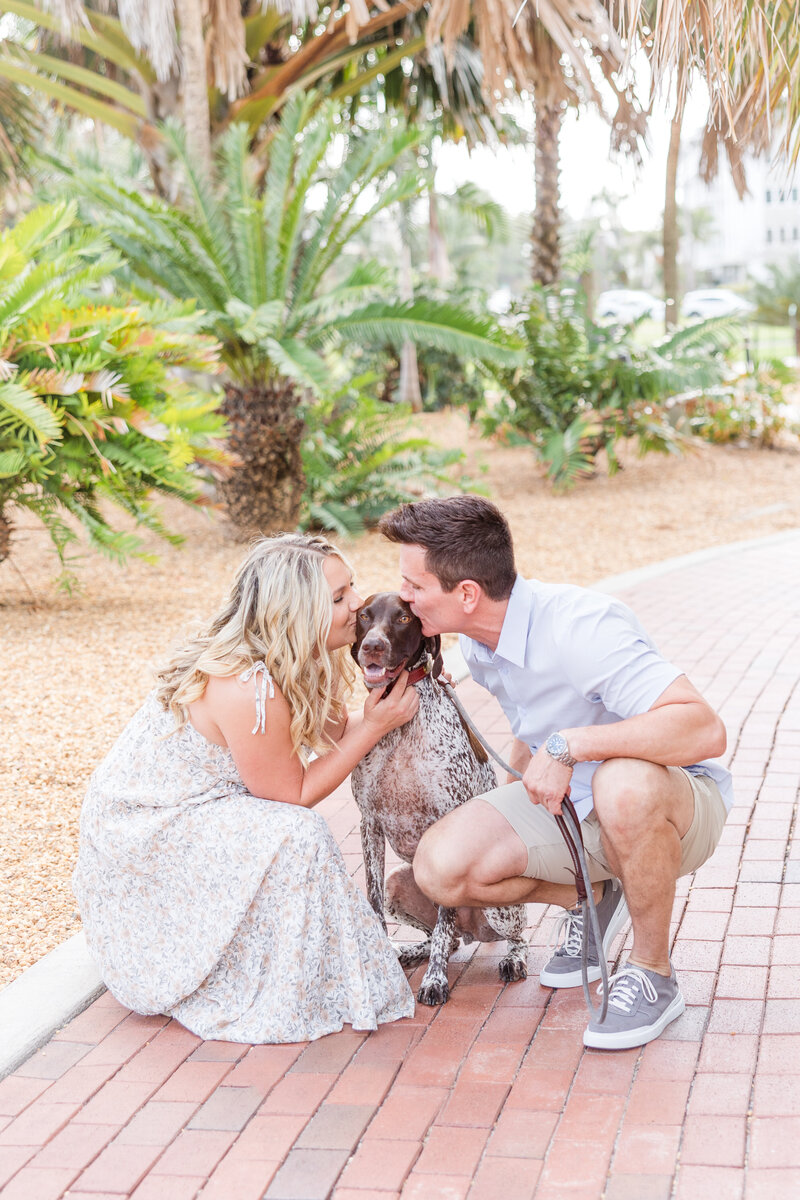 engaged couple kissing their dog