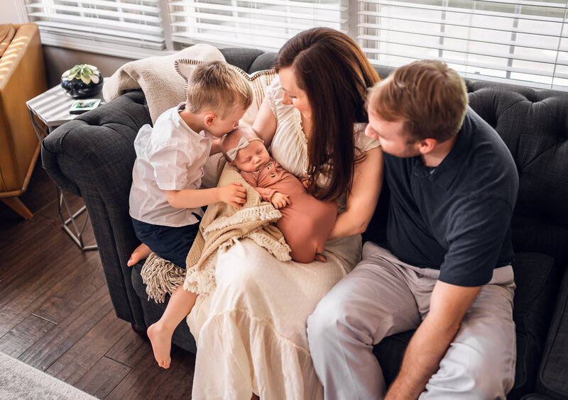 Family holding newborn baby at home