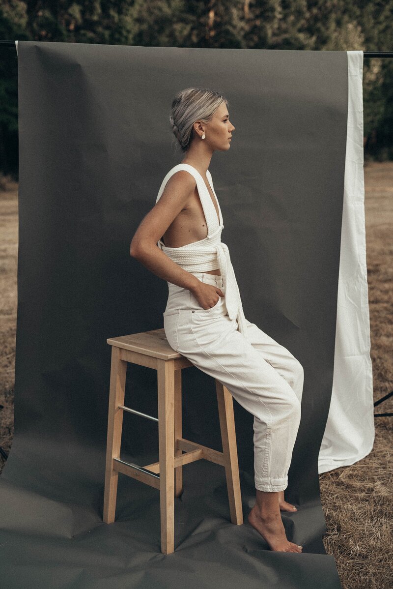 Model sitting on a bar stool in front of a backdrop in a field