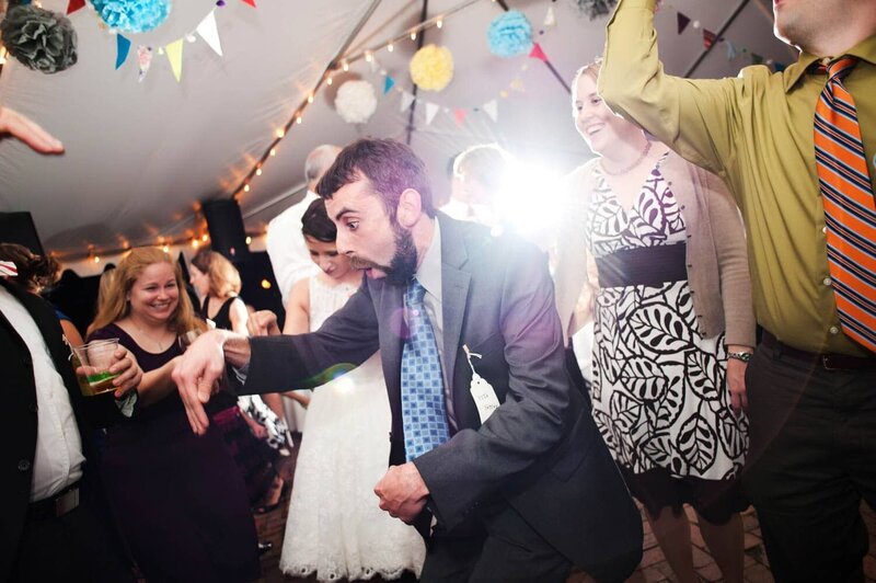 a man dances crazily as people laugh at him during a wedding reception