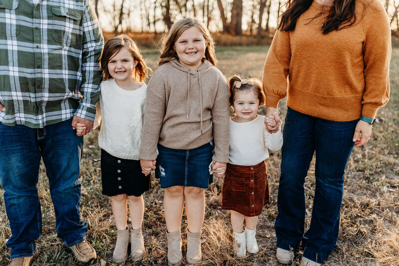 Family standing with three cute girls holding hands