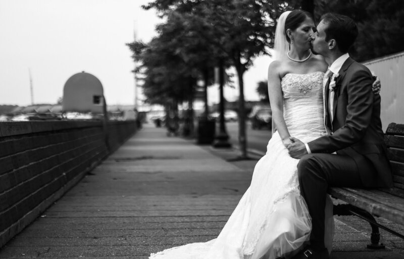 Kissing couple sitting on a  bench along walkway at Erie, PA's Dobbins Landing
