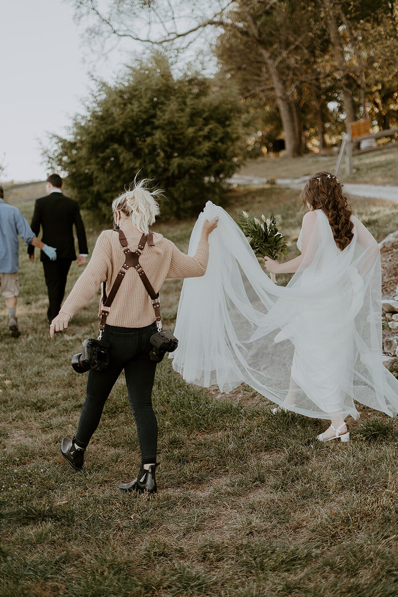 Kylee walking with a bride and holding her dress up