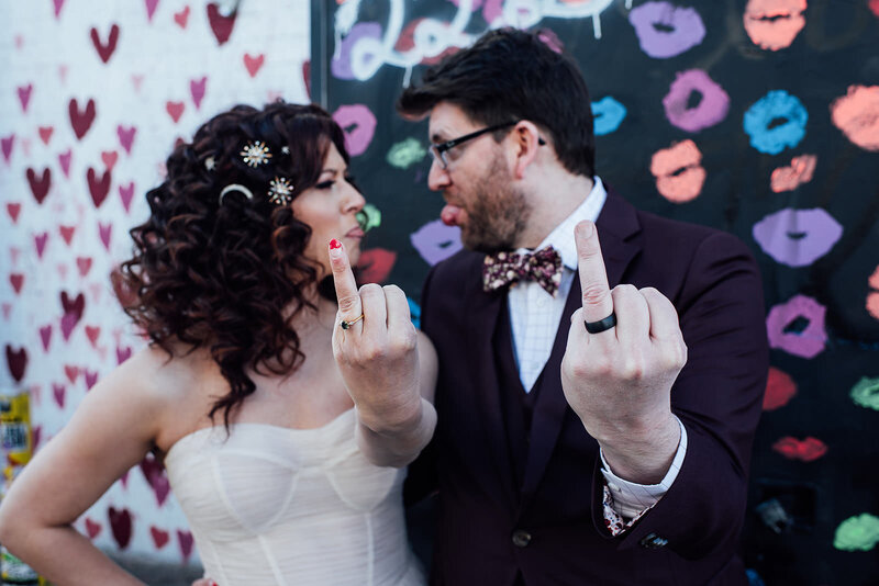 A bride and groom holding out their ring fingers.
