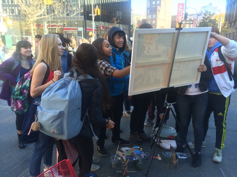 A group of passerbyers working on a collaborative painting in NYC