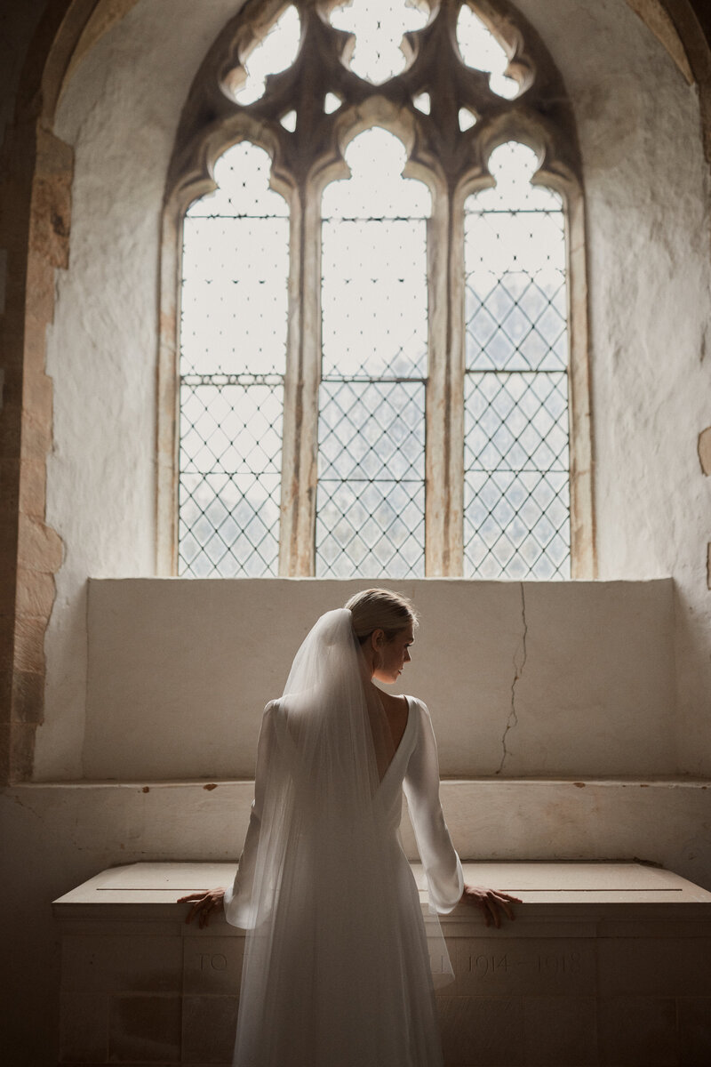 Long sleeve wedding dress in silk, Vanity Fair photography in church of bride
