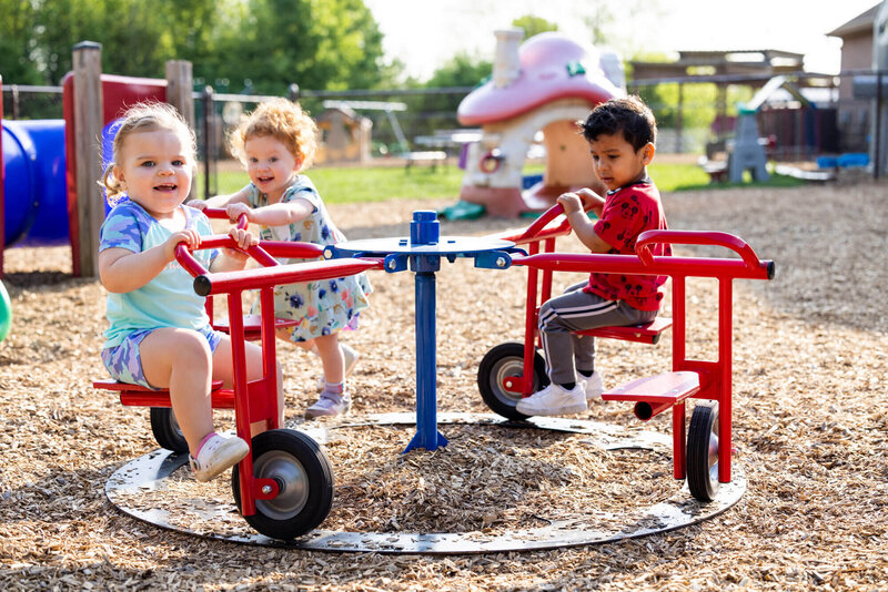 toddlers playing outside on the merry go round