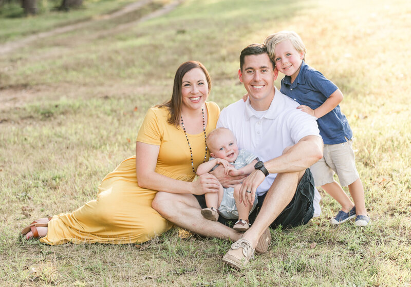 Family sitting in a grassy field during their portrait session