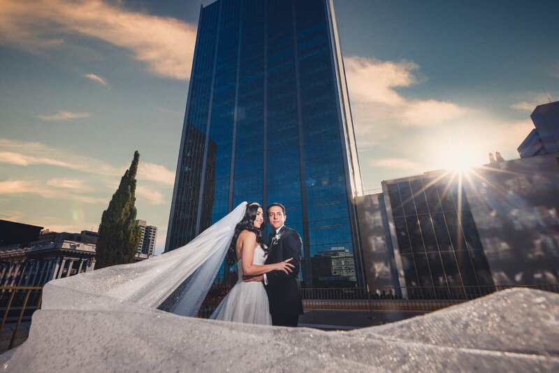 Bride and groom portrait with long flowing veil standing in front of high rise buildings at the Westgate Hotel, San Diego