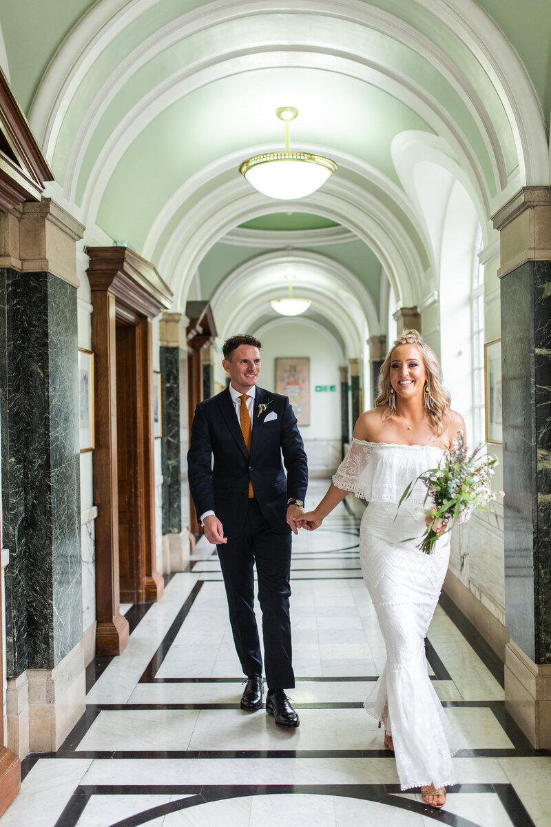 Bride and groom walking  casually after wedding ceremony in marbled hallway