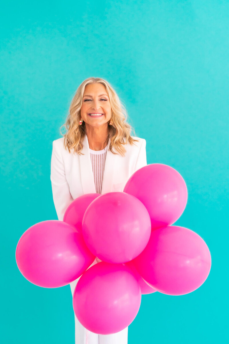 White suit Ashley with pink balloons confident in targeting the right customers.