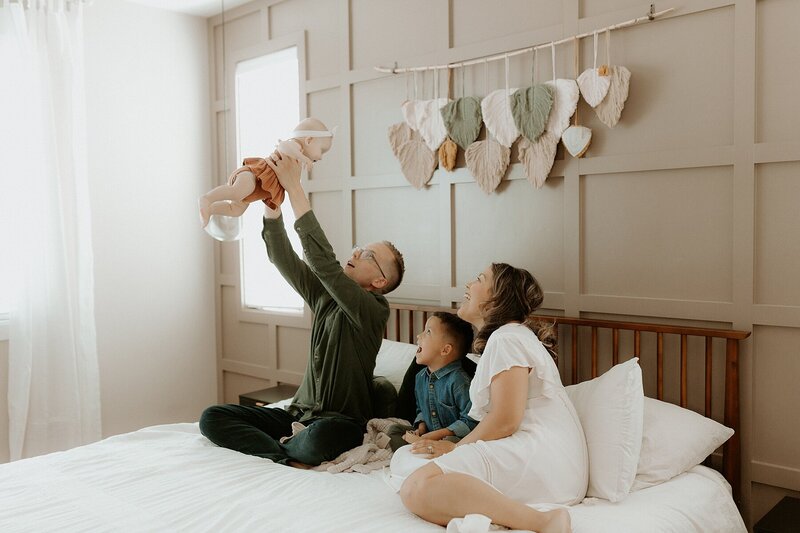 A family holding a baby on a bed in a bedroom.