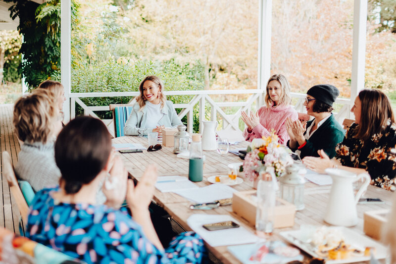 Group of business women sat around a table with Emily Osmond.