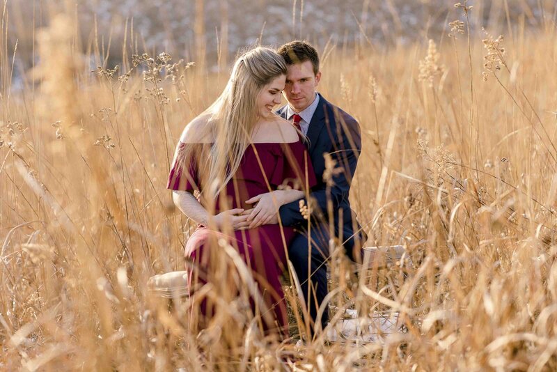maternity photos of mom in red dress with male in field