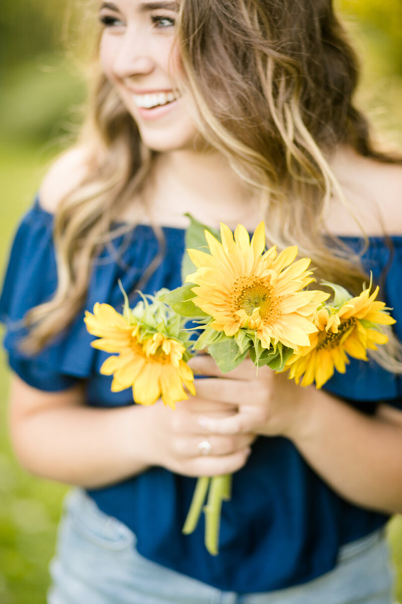 Girl holding a bouquet of sunflowers.