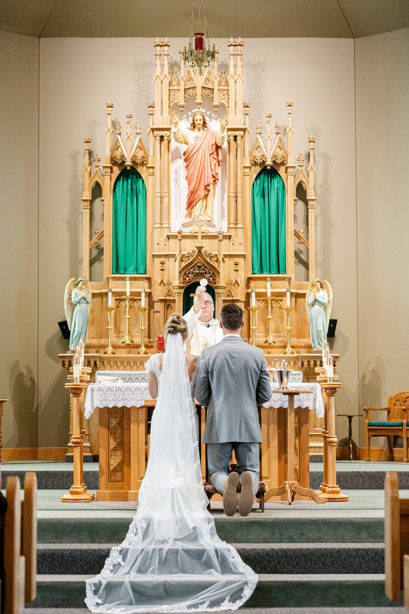 Priest elevates the eucharist during catholic wedding mass in York, Nebraska at church of saint joseph