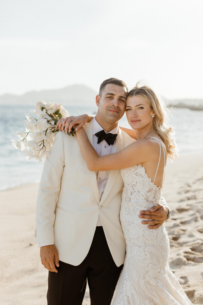 bride and groom holding each other on the beach