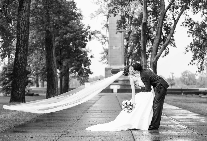 Bride and groom kiss as winds lift the veil at Perry Monument on Presque Isle State Park