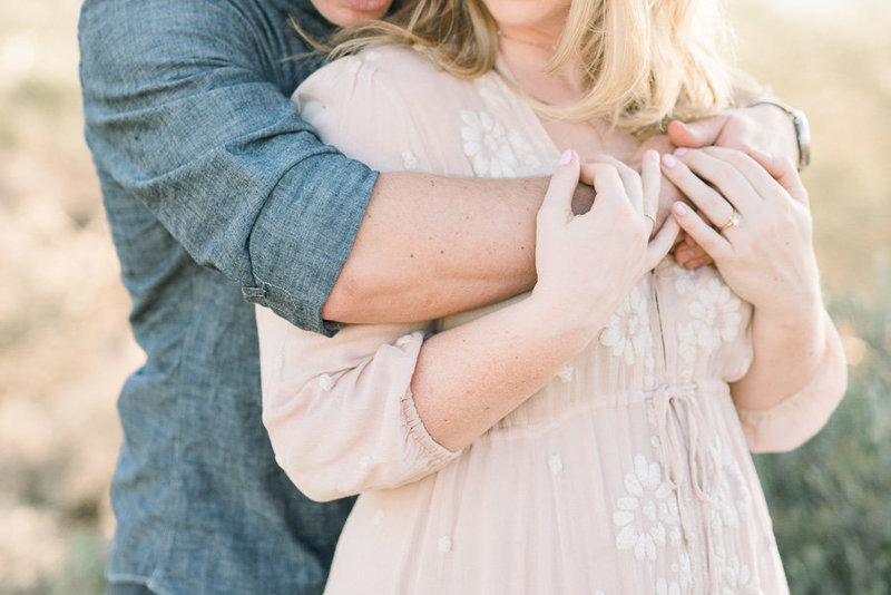 Tucson Desert Engagement Session Photo at Gates Pass of Couple Embracing and Showing Engagement Ring | Tucson Wedding Photographer | West End Photography