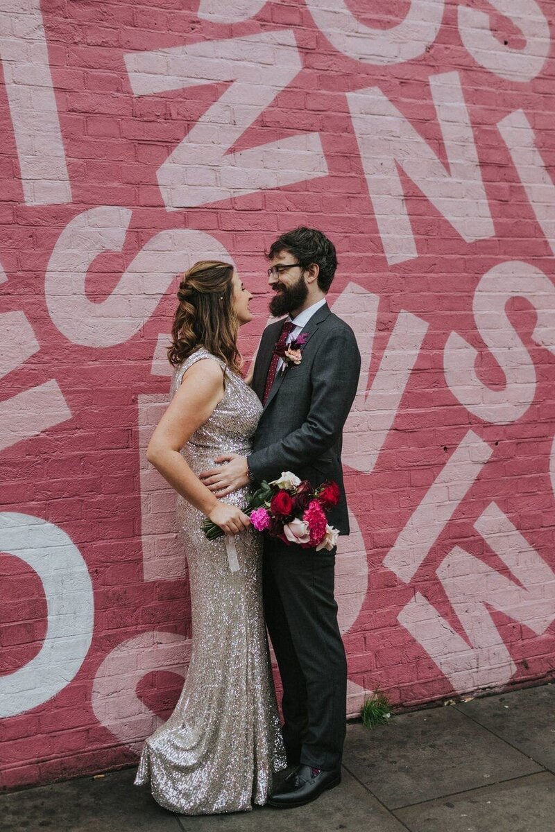 Bride and groom in front of pink alphabet mural
