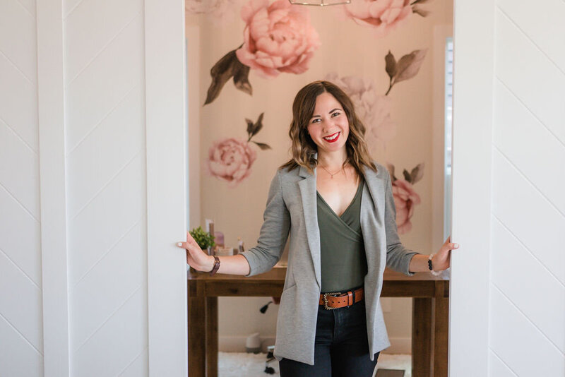 Woman smiling at the camera opening the doors to an office with flowered wallpaper