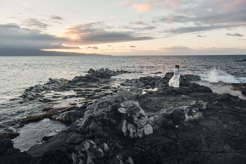 Couple embraces each other as waves crash upon them