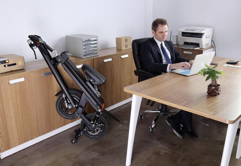 Black Go-Bike M2 folded up in office while sales rep works on his computer