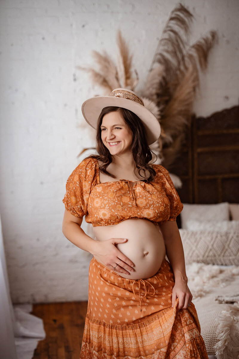 Pregnant mother in a two piece set smiling and holding her belly.