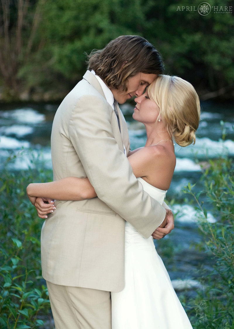 Romantic photo of bride and groom next to Blue River at Silverthorne Pavilion Summer wedding