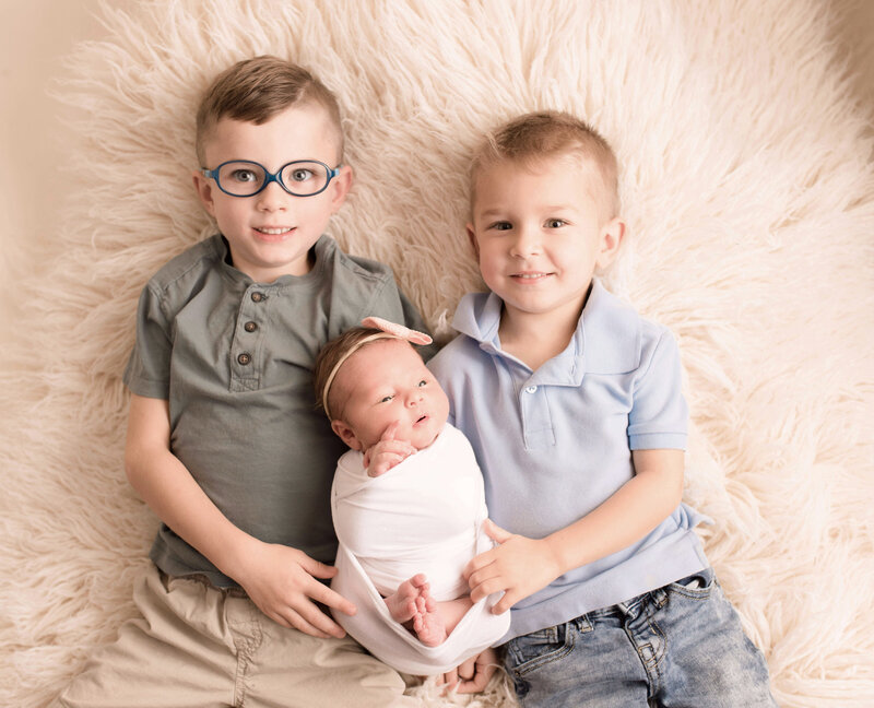 2 brothers holding their new baby sister