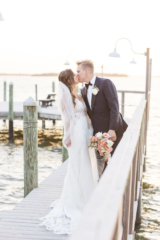 bride and groom kissing on a pier