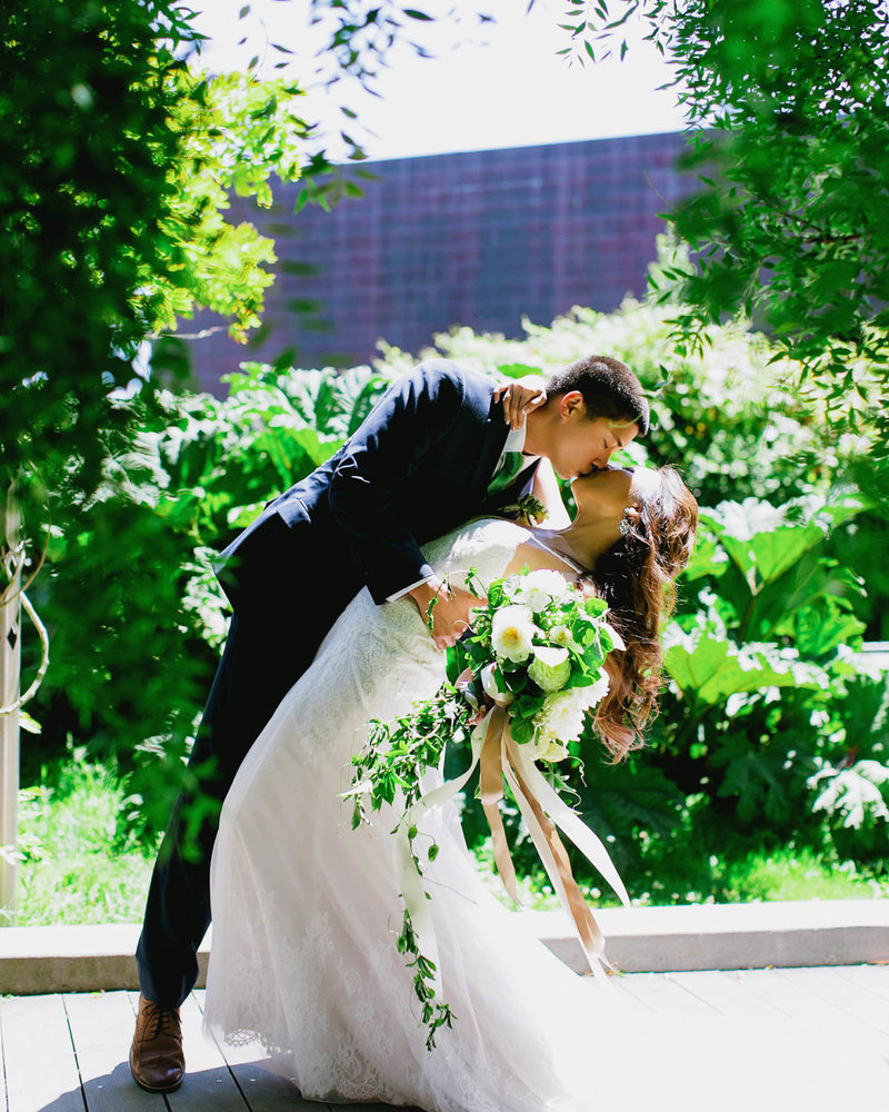 Groom holding Bride as they lean and kiss one another