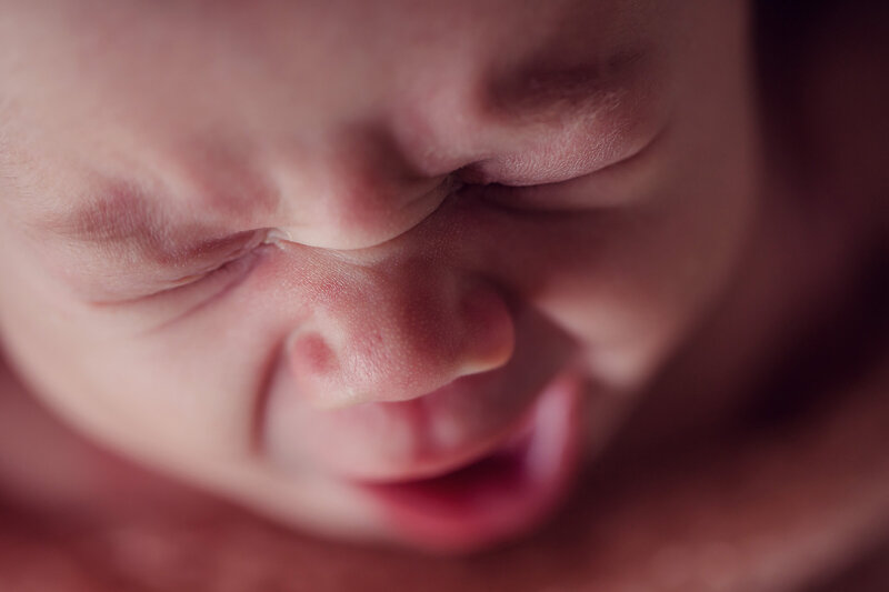 Close up photo of a newborn baby while they have a big yawn.