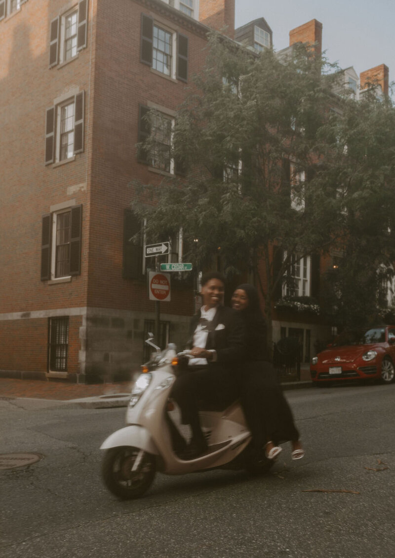 an anniversary session of a couple together riding a moped down the streets of Boston